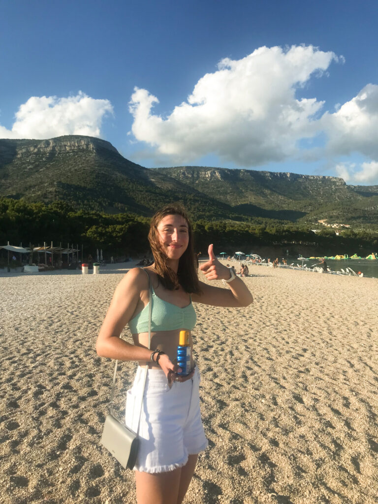 Girl Holding Sunscreen and Thumbs Up at Zlatni Rat Beach, Bol, Croatia