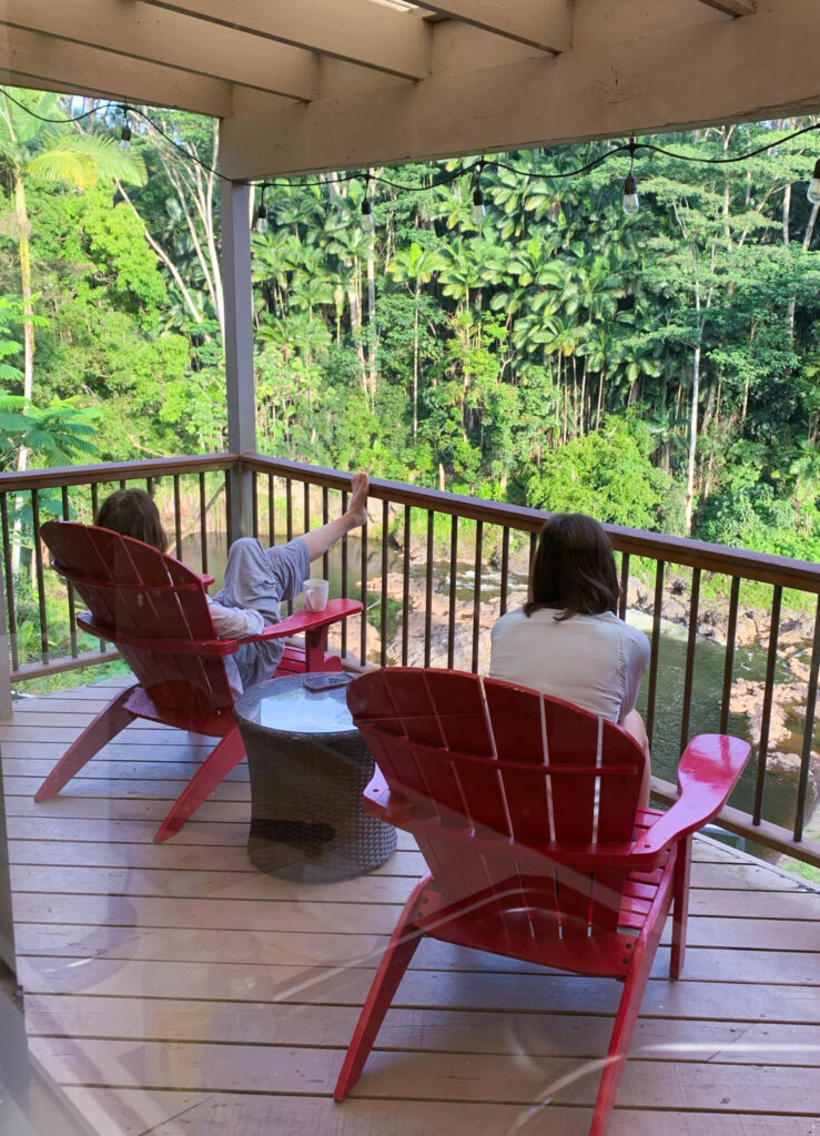 Two Women Sitting on Red Adirondack Chairs