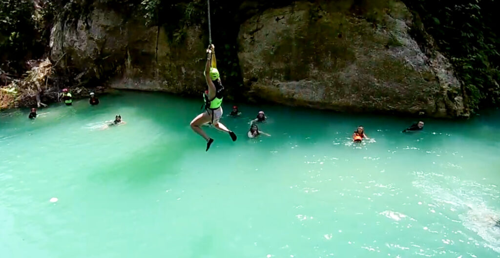 Girl jumping into water in Kawasan Falls