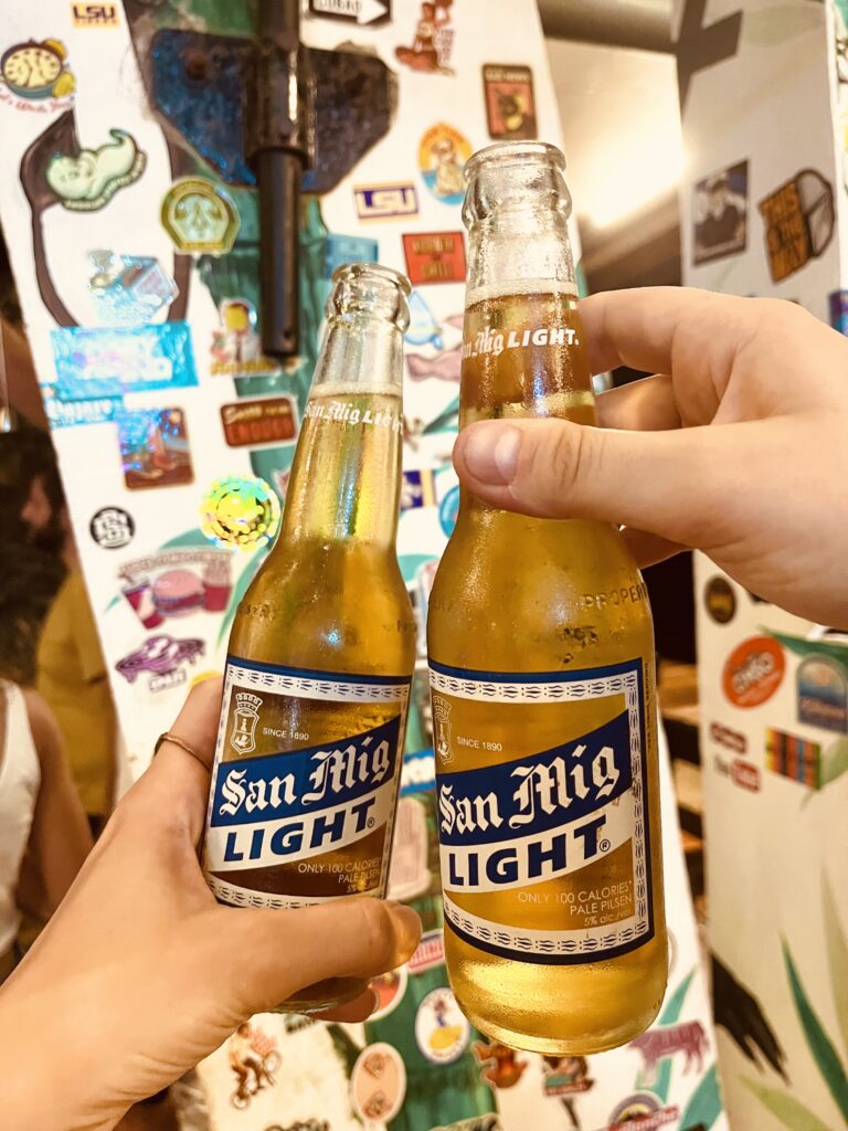 2 San Miguel Light Beers in front of a sticker wall