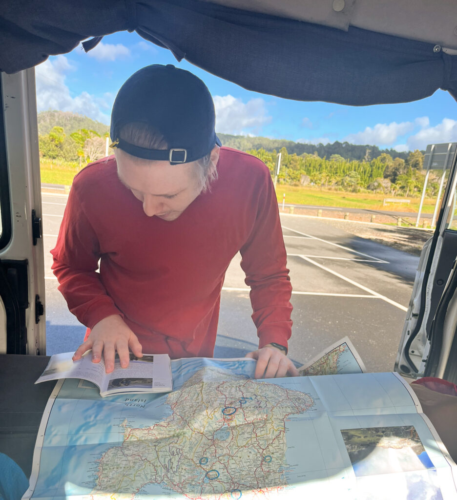 Man with red shirt leaning over a map of the North Island